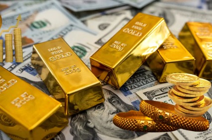 Gold jewellery and coins displayed with price tags representing 18K, 22K, and 24K purity rates in India.