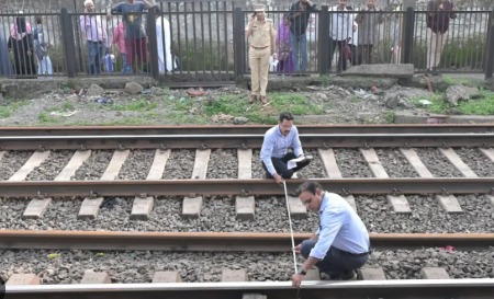 Rescue workers and passengers at the site of the Mumbra train accident near Mumbai, showing damaged tracks and halted trains