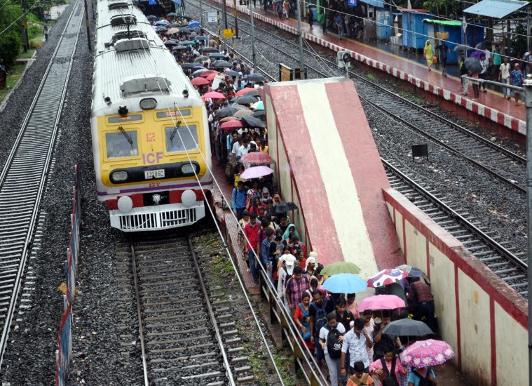 Emergency responders at Mumbai local train station after accident, with injured being attended to and train halted