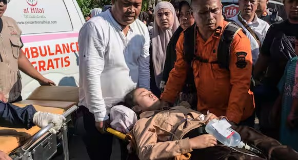 Rescue personnel assisting injured students and staff after an explosion at a school mosque in Indonesia during Friday prayers.