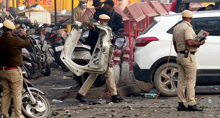 Security personnel inspecting a damaged car near Delhi’s Red Fort after the November 2025 explosion, with forensic teams on-site