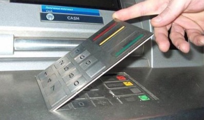 Card skimming warning with a hand inserting a debit card into an ATM slot.