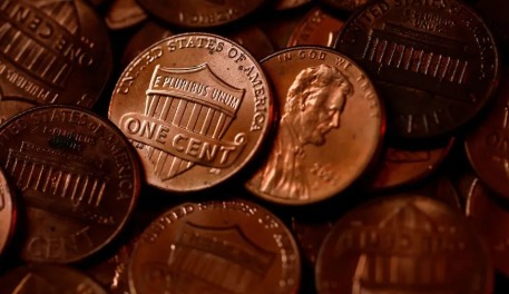 US pennies stacked together with one-cent coin highlighted after discontinuation announcement.