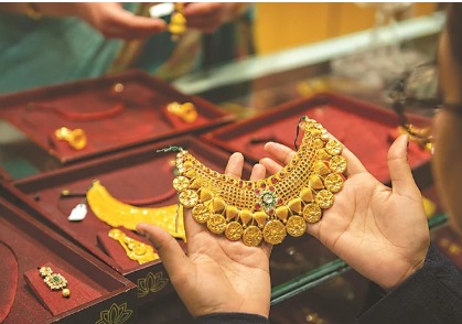 A jeweller’s display of 24-carat gold bars and coins with price tags in an Indian jewellery shop signifying current gold rate trends.