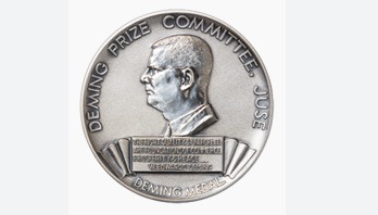 Manufacturing facility team celebrating Deming Prize achievement with quality-excellence certification display.