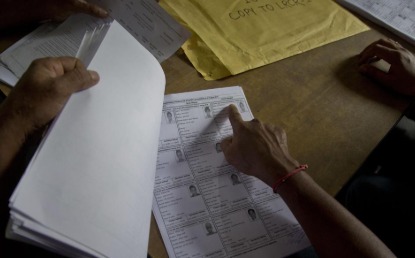 Assam election officials reviewing electoral roll documents during revision process at polling office.