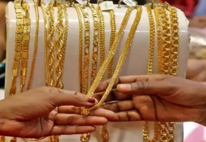 Gold bars and jewellery with city-wise gold price board showing 24K, 22K and 18K gold in India
