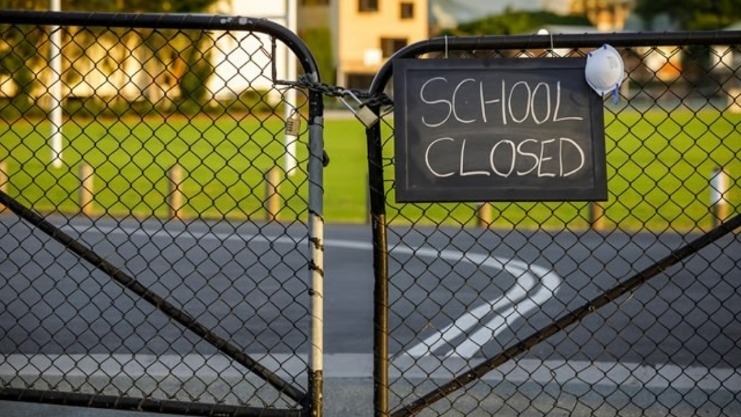 Closed school gate with notice board announcing holidays in winter months